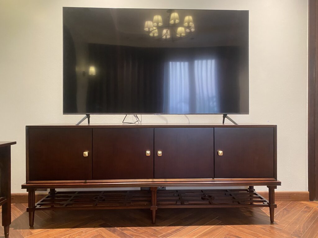 Kệ tivi Adaline tân cổ điển bốn cánh trơn, đế có tầng nan gỗ, đặt TV lớn trong phòng khách