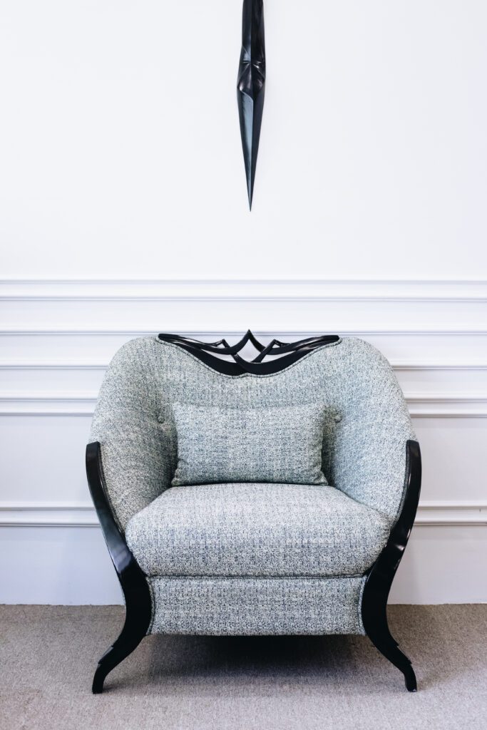 Armchair Augustus tân cổ điển bọc vải xám, tựa lưng có chi tiết gỗ đen chạm hình vương miện, chân cong sơn đen