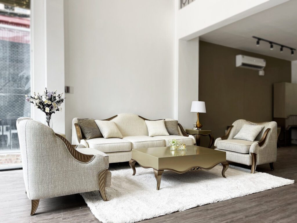 Hai armchair Il Finale tân cổ điển bọc vải kem, khung gỗ vân sóng ánh kim, đặt hai bên sofa Il Finale và bàn trà ánh kim trên thảm lông trắng