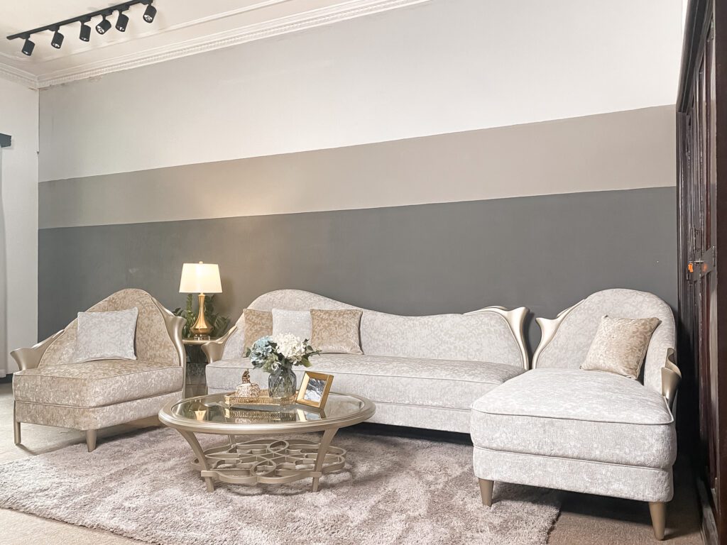 Bàn trà Di Angelo tân cổ điển mặt kính tròn, đế đan vòng cong ánh kim, đặt giữa sofa góc màu be