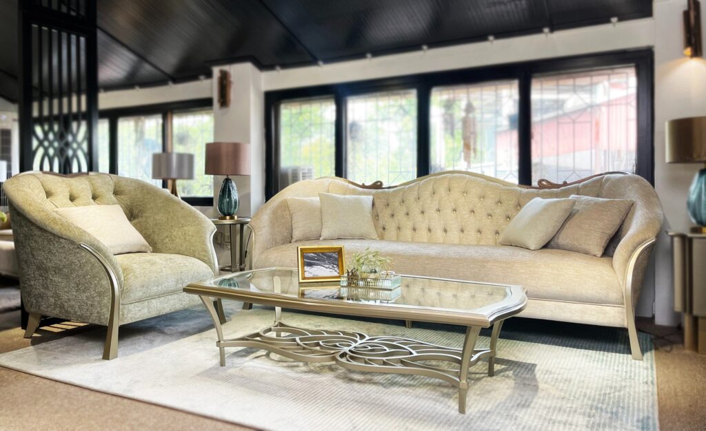 Bàn trà Victoire tân cổ điển mặt kính chữ nhật, đế hoa văn ánh kim, trước sofa Victoire tựa lưng chần nút